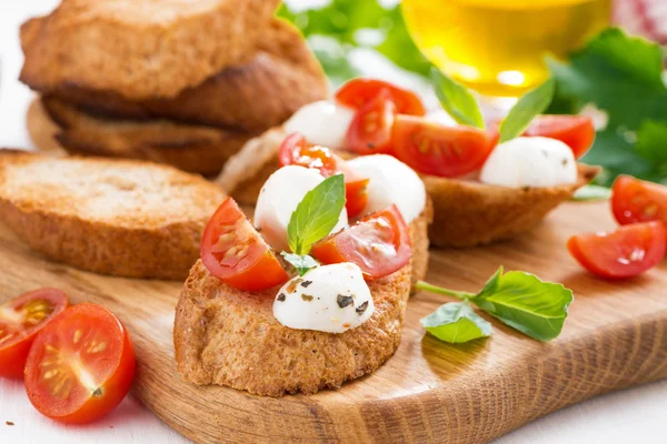 Bruschetta con mozzarella, albahaca y tomates cherry —  Fotos de Stock