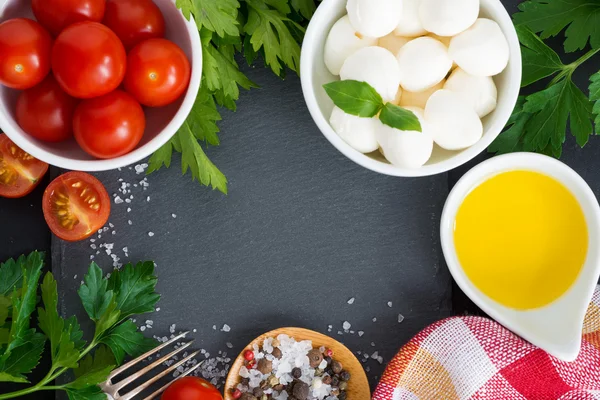 Mozzarella, Zutaten für den Salat und schwarzer Hintergrund — Stockfoto