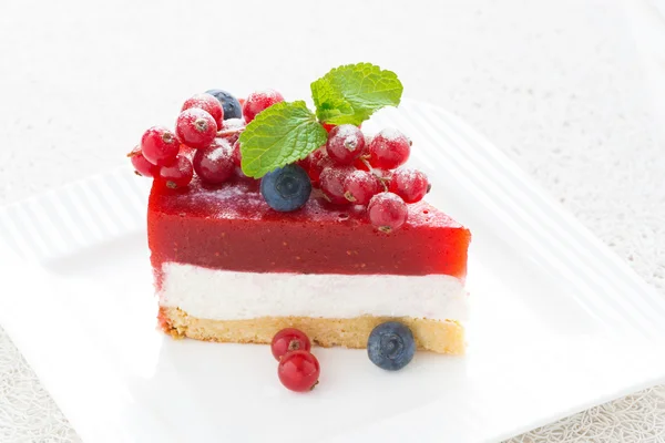 Pedazo de pastel de queso con gelatina de fresa en un plato, primer plano — Foto de Stock