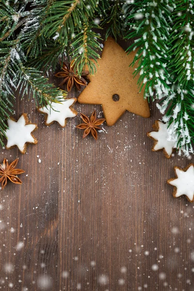 Wooden background with fir branches, cookies and snow bokeh — Stock Photo, Image