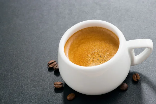 Espresso su sfondo scuro e chicchi di caffè, vista dall'alto — Foto Stock