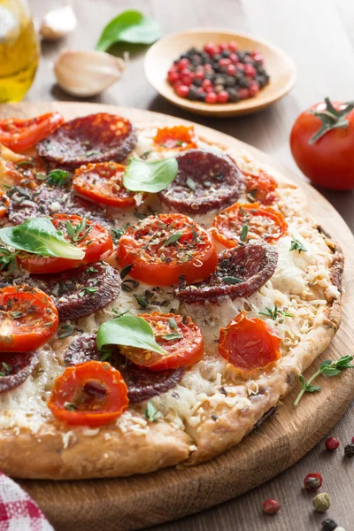 Italienisches Essen - Pizza mit Salami und Tomaten an Bord, vertikal — Stockfoto
