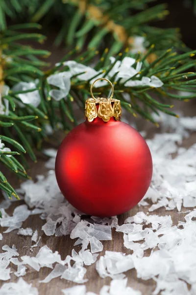 Boule de Noël rouge dans les branches de neige et d'épinette, gros plan — Photo