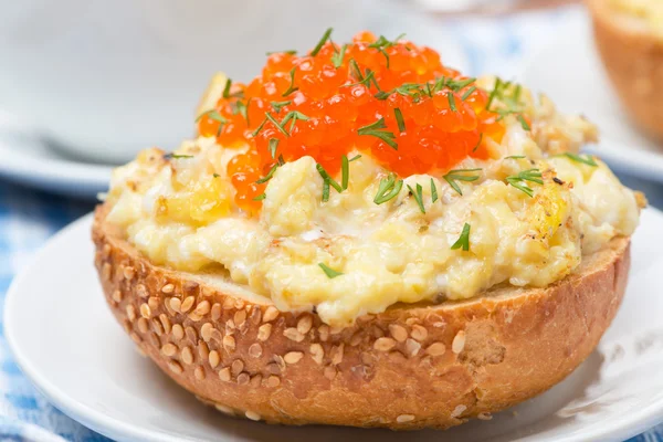 Scramble eggs with red caviar and greens on a bun — Stock Photo, Image