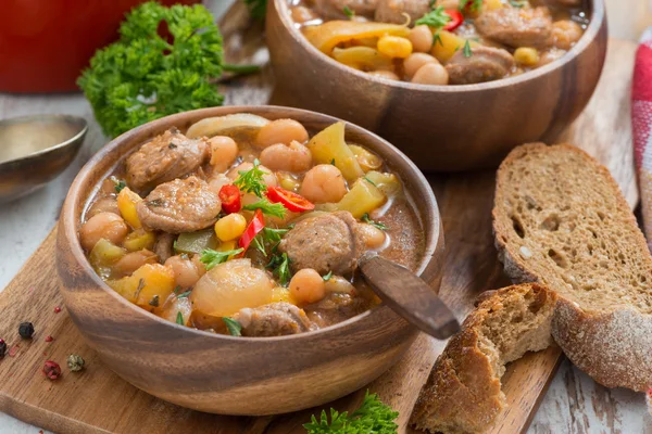 Vegetable stew with sausages in a wooden bowl on board and bread — Stock Photo, Image