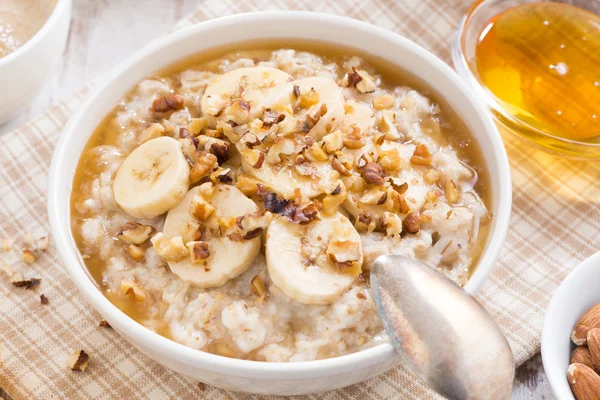 Hälsosam frukost - havregrynsgröt med banan, honung och valnötter — Stockfoto