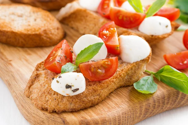 Bruschetta med mozzarella, basilika och körsbärstomater, närbild — Stockfoto