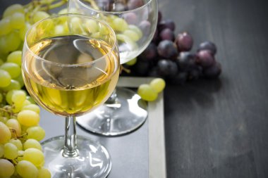 Kadeh beyaz şarap ve üzüm yatay bir kara tahta üzerinde