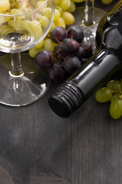 Bottle of red wine, empty glass and grapes on wooden background — Stock Photo, Image