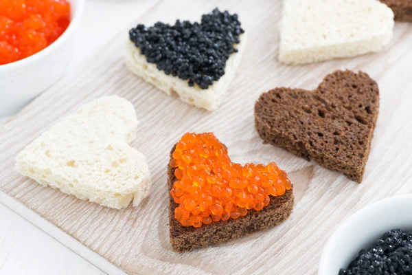 Festive appetizer - toasts in heart shape on wooden board — Stock Photo, Image