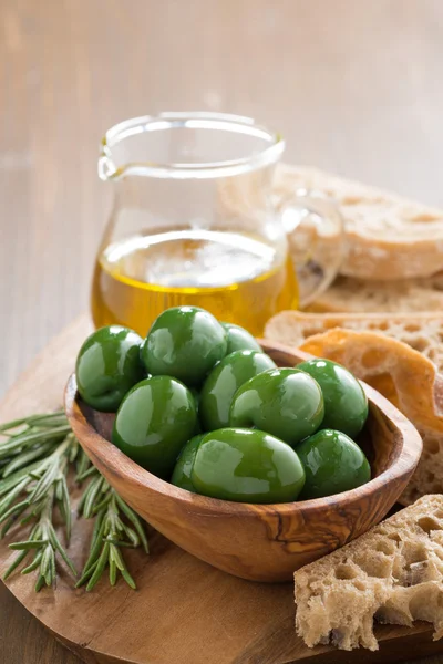 Fresh green olives, olive oil and ciabatta on wooden board — Stock Photo, Image