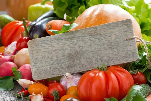 Surtido de verduras frescas de temporada y una placa de madera — Foto de Stock