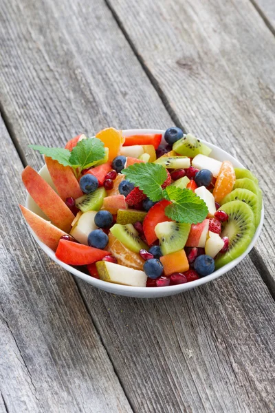 Salada de frutas e bagas em mesa de madeira, vertical — Fotografia de Stock