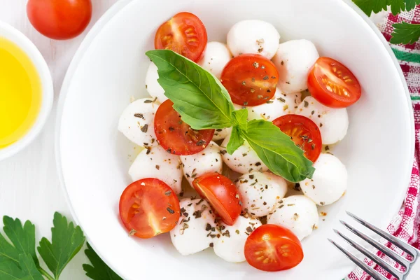 Salad with mozzarella, basil and cherry tomatoes in bowl — Stock Photo, Image