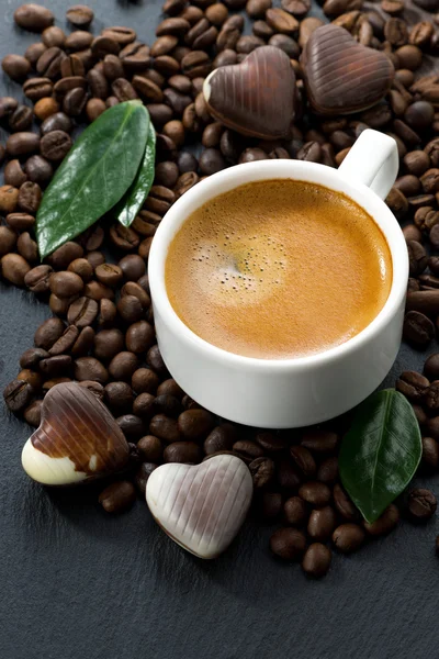 Cup of espresso on coffee beans background and chocolate candies — Stock Photo, Image