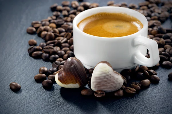 Kopp espresso, kaffebönor bakgrund och choklad godis — Stockfoto