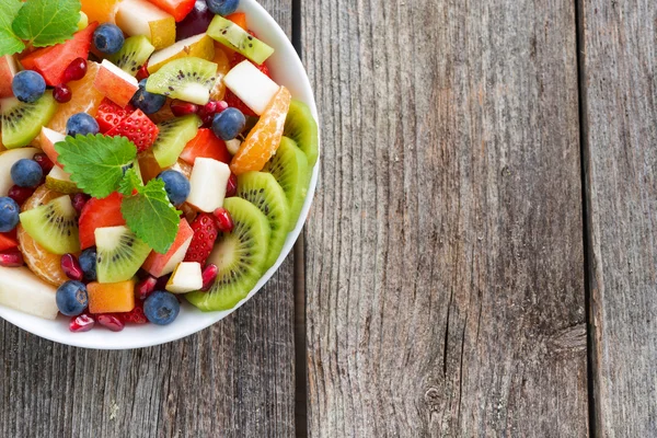 Obst- und Beerensalat und Holzhintergrund, horizontal — Stockfoto