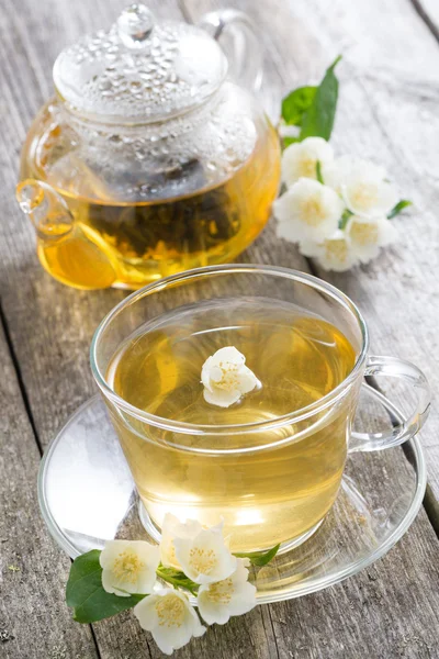 Konvice a šálek zeleného čaje s jasmine na dřevěný stůl — Stock fotografie