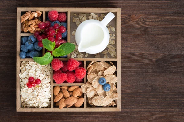 Dřevěný box s snídaní předměty - ovesné vločky, müsli, ořechy, bobule — Stock fotografie