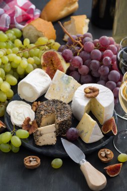 Yumuşak lezzetli peynir ve aperatifler için karanlık bir arka plan üzerinde şarap