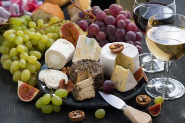 Yumuşak lezzetli peynir ve aperatifler için karanlık bir arka plan üzerinde şarap