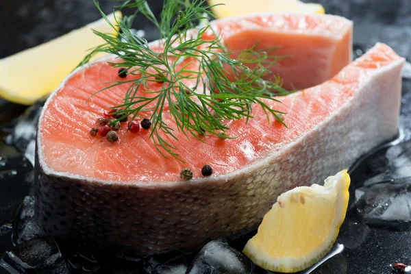 Raw salmon steak with dill and lemon on ice, close-up — Stock Photo, Image