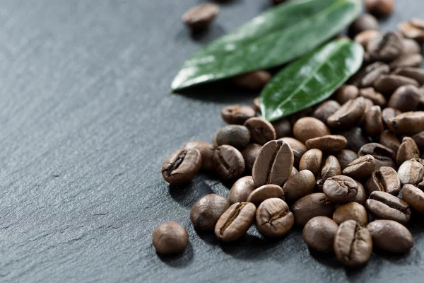 Roasted coffee beans and leaves on a dark background — Stock Photo, Image