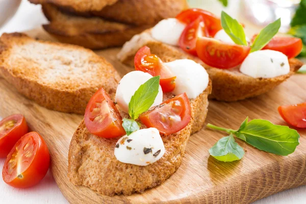 Bruschetta with mozzarella, basil and cherry tomatoes — Stock Photo, Image