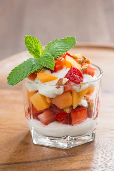 Fruit dessert with whipped cream and granola in a glass — Stock Photo, Image