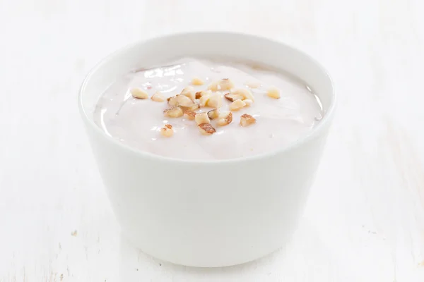 Romige yoghurt met noten in een witte kom — Stockfoto