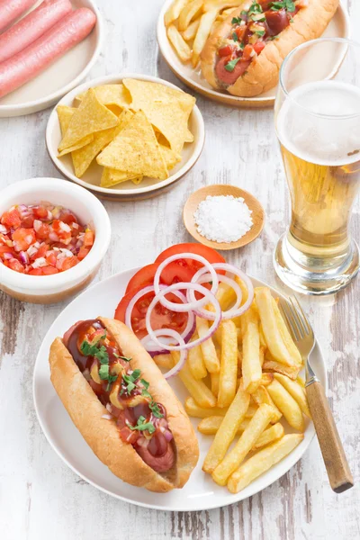 Comida rápida - hot dog con papas fritas, cerveza y aperitivos, vertical —  Fotos de Stock