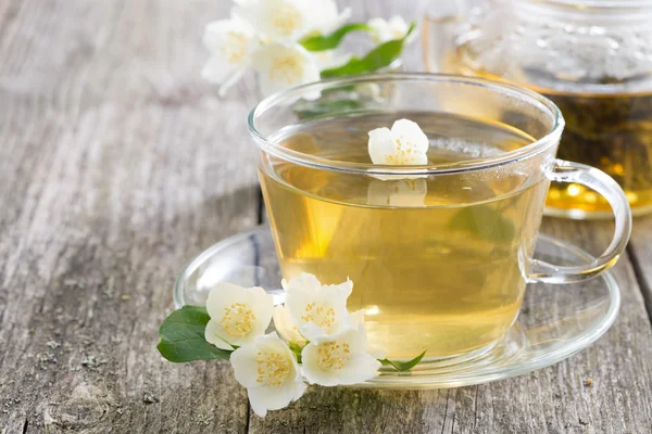 Glass cup of green tea with jasmine on wooden background — Stock Photo, Image