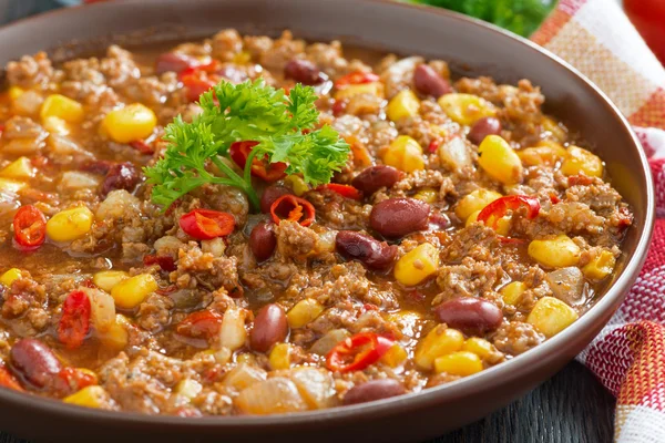 Spicy Mexican dish chili con carne in a brown pottery plate — Stock Photo, Image