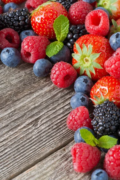 Holzhintergrund mit frischen Beeren und Minze, senkrecht — Stockfoto