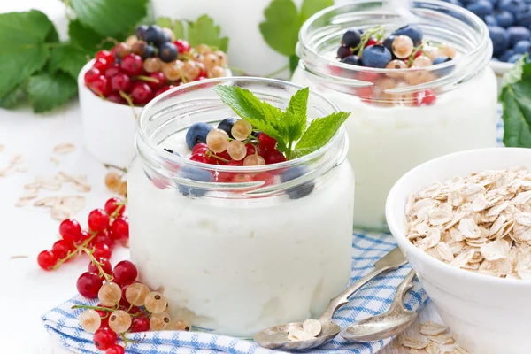 Yoghurt met verse bessen en ontbijt voedsel op tafel — Stockfoto