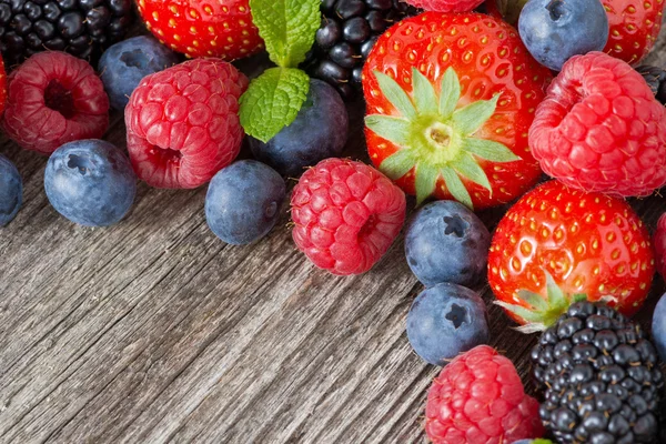 Holzhintergrund mit frischen Beeren und Minze, horizontal — Stockfoto