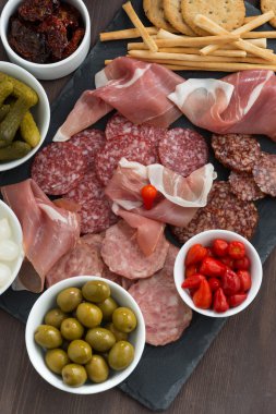 Çeşitli Şarküteri et aperatifler, sosis ve bir kara tahta üzerinde turşu,