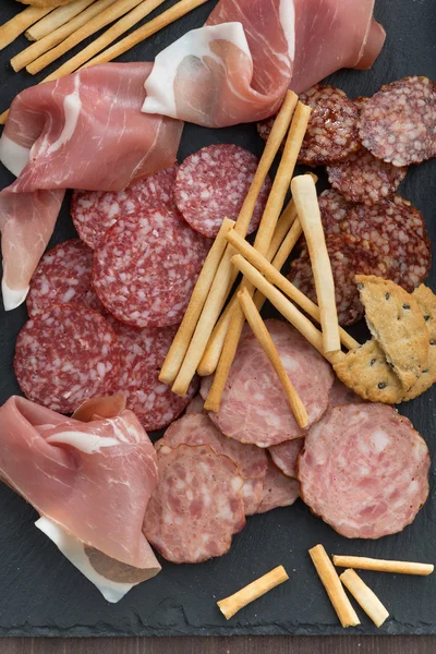 Snack di carne assortiti e sottaceti su una lavagna, vista dall'alto, clos — Foto Stock