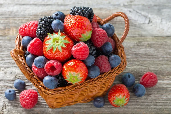 Korb mit frischen saisonalen Beeren auf Holztisch, Nahaufnahme — Stockfoto