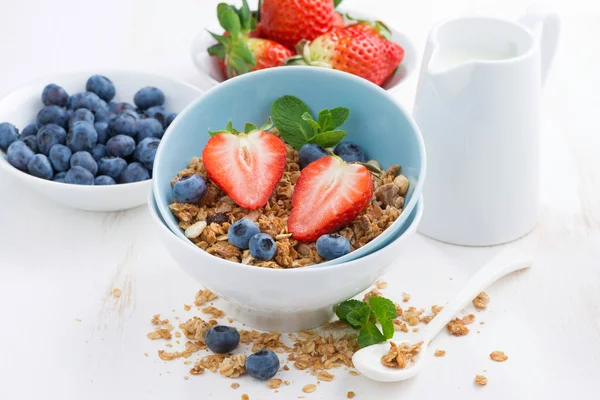 Zdravé potraviny - müsli, čerstvé jahody a mléko na bílém stole, c — Stock fotografie