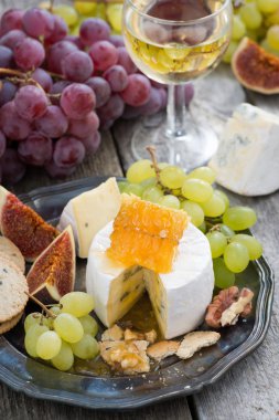 Camembert tatlım ve meyve, aperatifler ve şarap bir tabakta, dikey