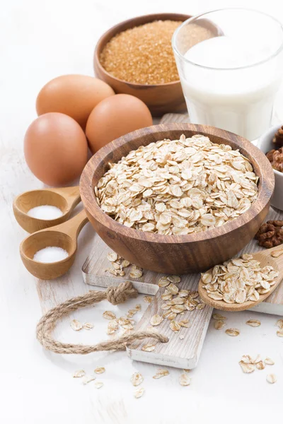 yulaf gevreği ve malzemelerin üzerine beyaz bir ahşap masa, dikey