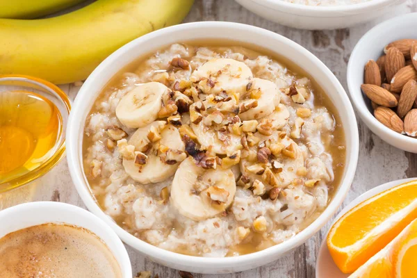 Hälsosam frukost - havregrynsgröt med banan, honung och valnötter i bo — Stockfoto