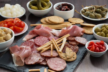 Çeşitli et aperatifler ve bir kara tahta üzerinde turşu