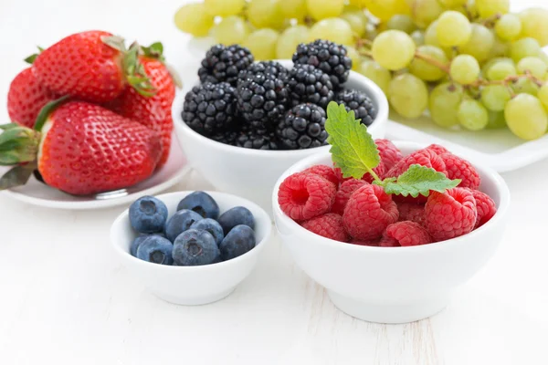 Fresh berries and grapes on a white wooden table, close-up — Stock Photo, Image