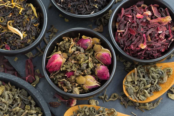 Assortiment van geurige droge thee in keramische kommen, close-up, top v — Stockfoto