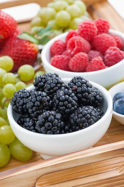 Bowl of blackberries, fresh berries and green grapes on a wooden — Stock Photo, Image