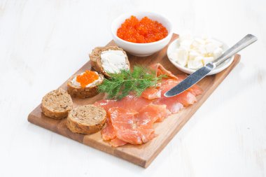 Tuzlanmış somon, kırmızı havyar, kızarmış ekmek ve tereyağı bir ahşap tahta üzerinde