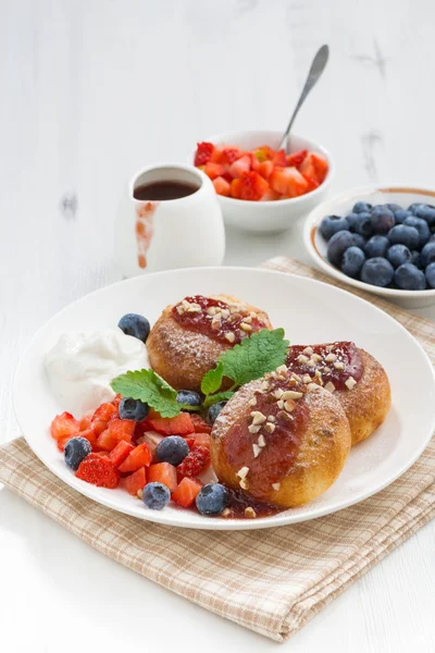 Söta ost pannkakor med färska bär och grädde på vitt trä — Stockfoto