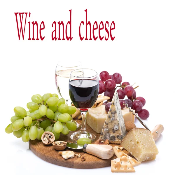 two glasses of wine, grapes and cheese assortment on a wooden bo